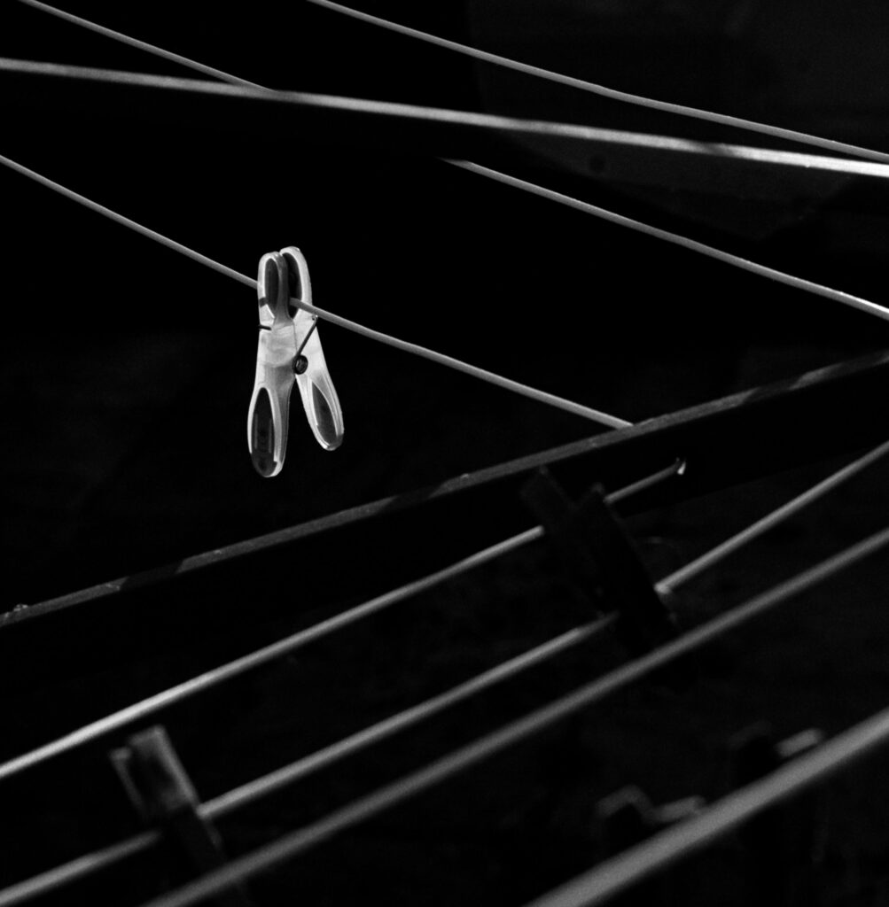 A high contrast picture of a clothes peg with the washing line criss-crossing the image
