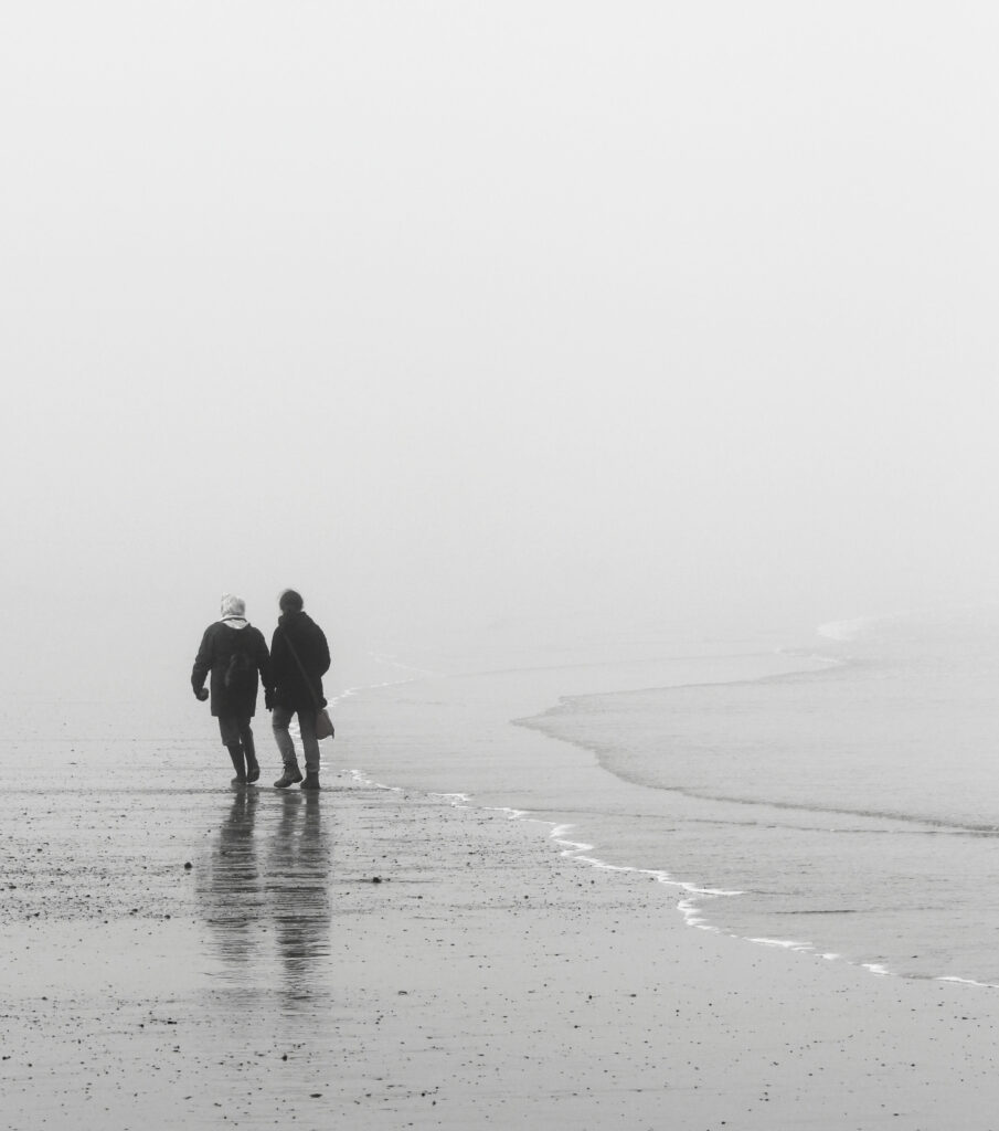 Two people at the edge of the sea in the mist