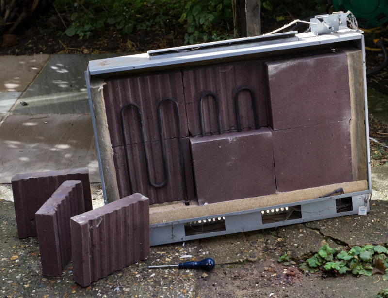 A storage heater with its side taken off, showing heat bricks around a heating element